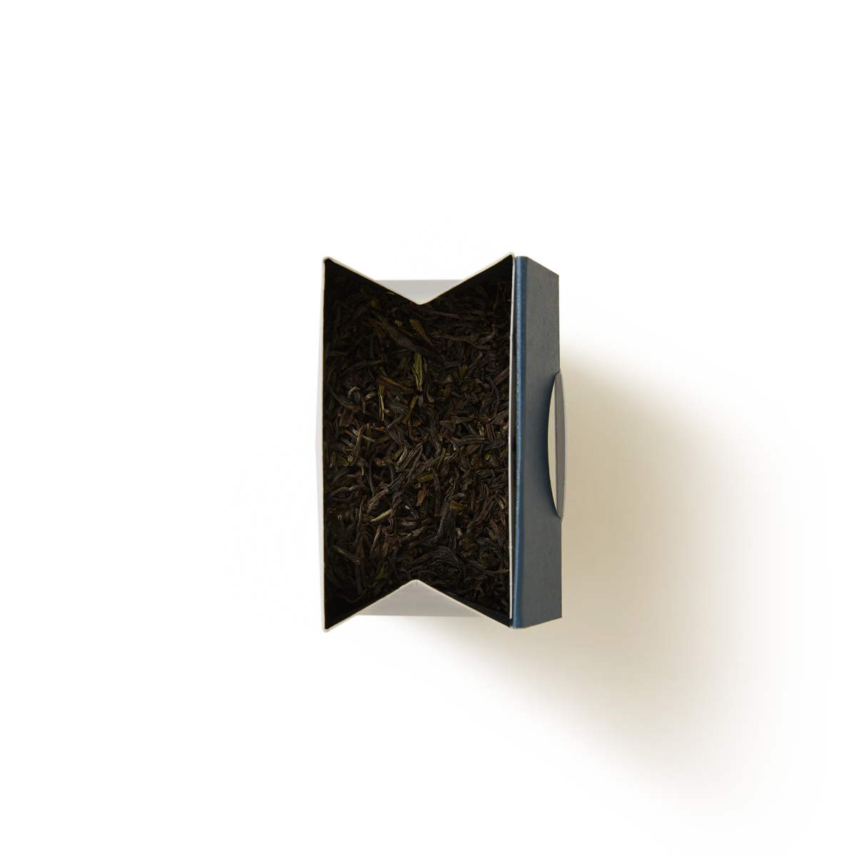 A top view of a blue, partially opened tea box filled with Margaret’s Hope 2026 First Flush Darjeeling Single Estate Loose Leaf Tea, casting a shadow on a white background.