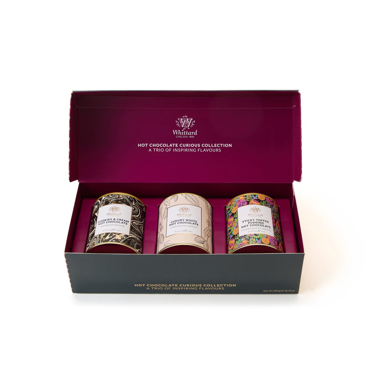 The Hot Chocolate Curious Collection features three tins of Whittard hot chocolate—including luxury white hot chocolate and cookies & cream hot chocolate—each in distinctively decorated containers, all arranged neatly inside an open magenta and black rectangular box on a white background.