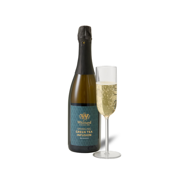 A bottle of Sparkling Green Tea Infusion is placed beside a filled champagne flute against a white background.