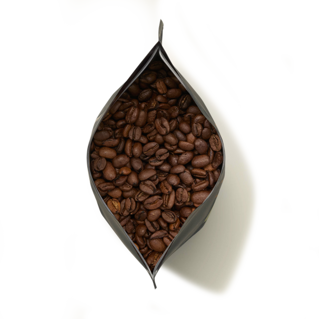 A black pouch of Limited Edition African Moon Coffee, open at the top and filled with roasted Ugandan Arabica coffee beans.