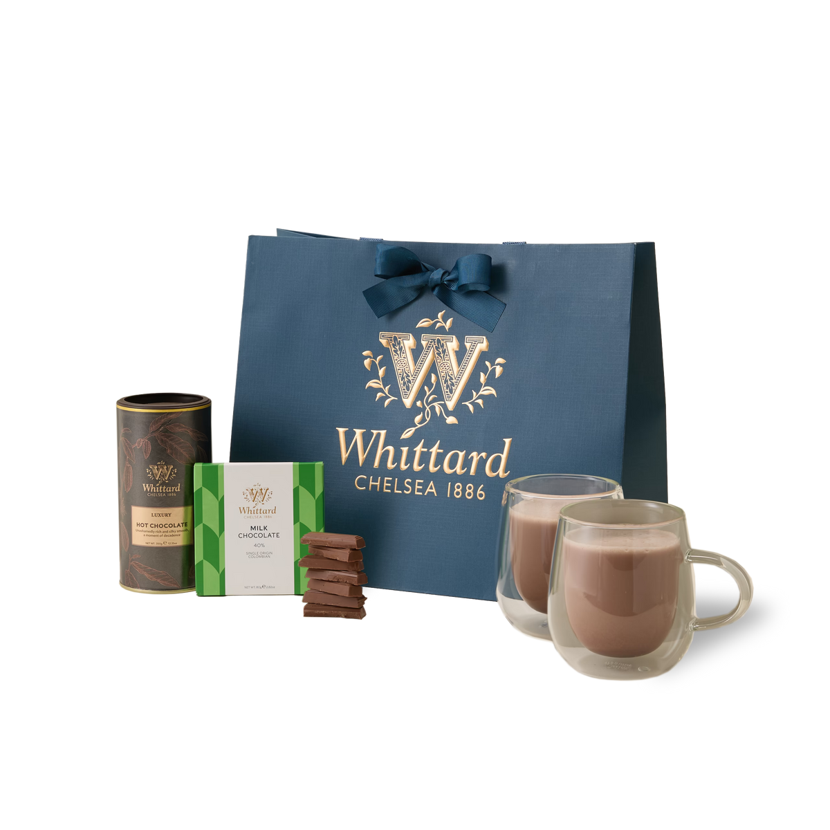 Introducing The Chocolate Indulgence Set: a luxurious hot chocolate gift set that includes a blue Whittard Chelsea 1886 bag, a tin of single origin Colombian milk chocolate hot chocolate, a box of assorted chocolates, several irresistible chocolate pieces, and two elegant glass mugs brimming with rich, velvety hot chocolate.