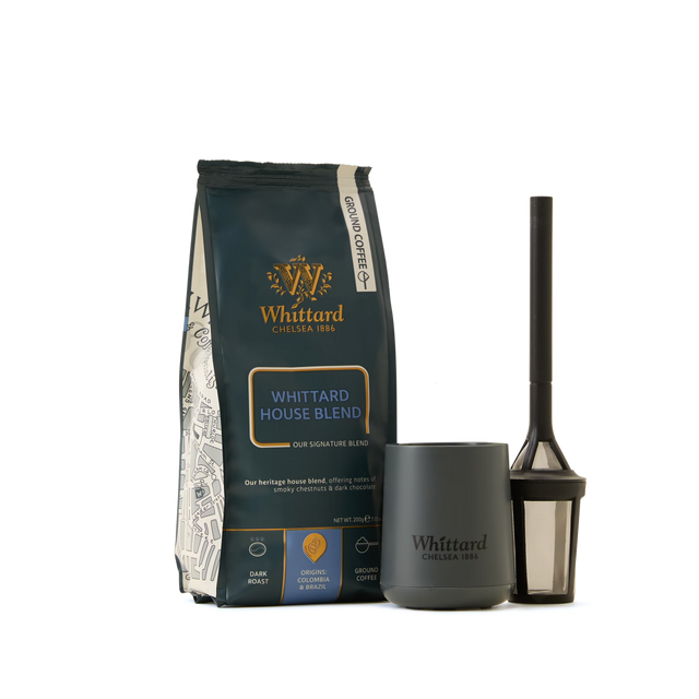 The Coffee Lovers Kit, featuring a Whittard House Blend coffee bag, a dark gray Whittard mug, and a black coffee press with mesh filter, all arranged on a white background—the ideal set for anyone who appreciates specialty coffee.