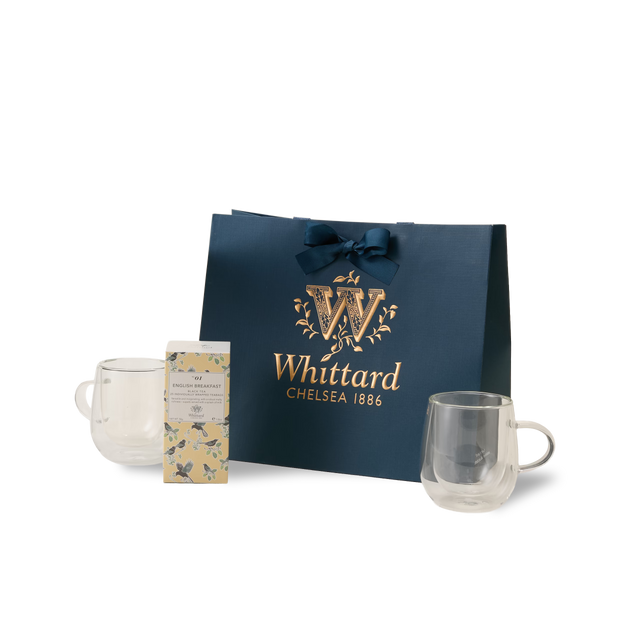 The Everyday Tea Gift Set features a navy blue Whittard Chelsea 1886 gift bag with a ribbon, two double-walled glass mugs, and a floral-designed box of English Breakfast tea containing individually wrapped teabags, all beautifully arranged against a white background.
