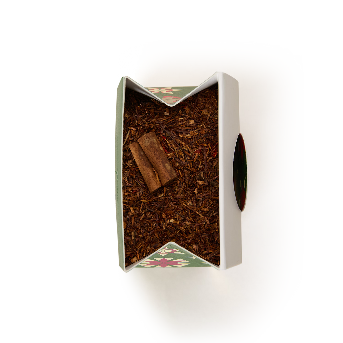 Top-down view of an open rectangular tin filled with Fireside Rooibos Loose Infusion and two cinnamon sticks, creating a warm seasonal infusion.