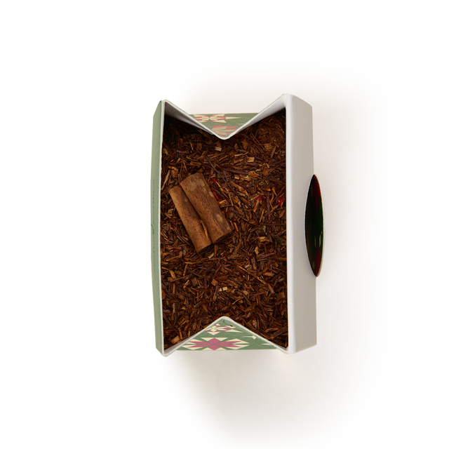 Top-down view of an open rectangular tin filled with Fireside Rooibos Loose Infusion and two cinnamon sticks, creating a warm seasonal infusion.