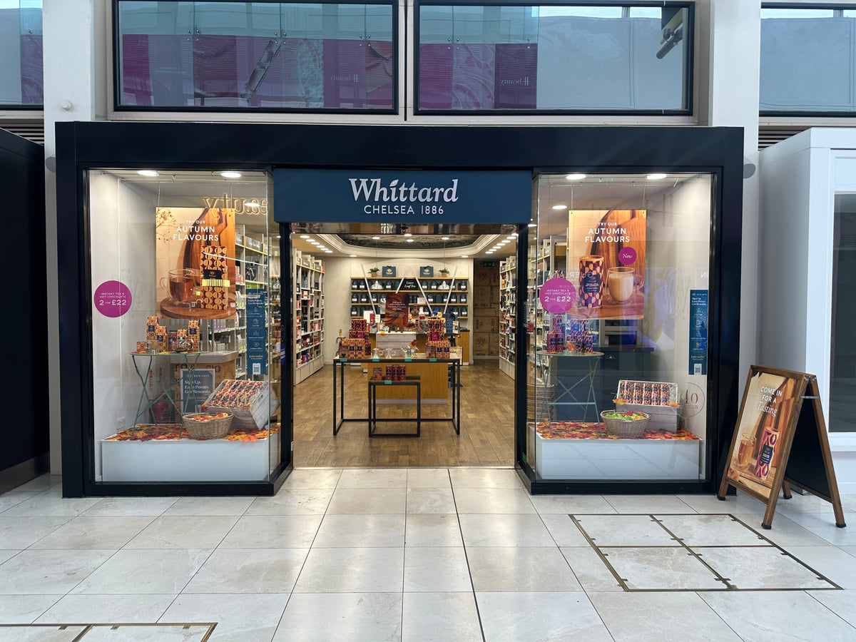 The storefront of Whittard Chelsea 1886, a traditional British confectionery, shown from the front. The shop features a black frame and a dark blue sign with white lettering.