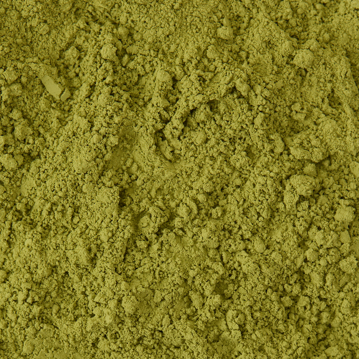 Close-up of loose Vanilla Matcha powder with a fine, crumbly texture, resembling sugar-free matcha or another green tea powder, spread evenly across the surface.