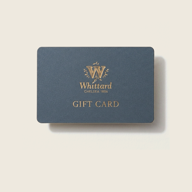 A dark blue Whittard of Chelsea E-Gift Card featuring gold text and logo that reads “Whittard Chelsea 1886 GIFT CARD,” displayed on a light beige background—the ideal gift for any occasion, providing recipients the freedom to choose their favourite blends and include a personal message.